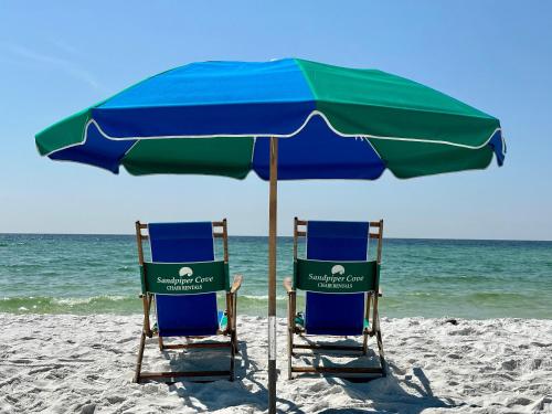 two chairs under an umbrella on the beach at Sandpiper Cove 8224 in Destin