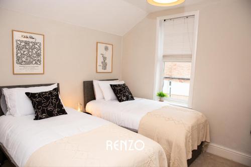 two beds in a small room with a window at Inviting 3-bed Home in Nottingham by Renzo, Victorian Features, Sleeps 6! in Nottingham