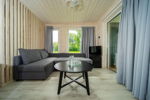 uma sala de estar com um sofá e uma mesa em Tiny house aan het water op de appelhof em Wommels