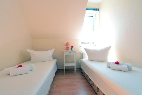 two white beds in a room with a window at Ferienwohnung Buchwald in Boltenhagen