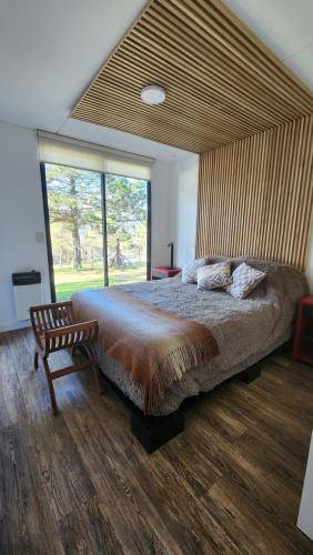 ein Schlafzimmer mit einem großen Bett und einem großen Fenster in der Unterkunft Colores de Manantiales in Villa General Belgrano