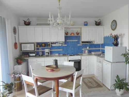 eine Küche mit weißen Schränken und einem Tisch und Stühlen in der Unterkunft Tulipán Panoráma Apartman in Pécs