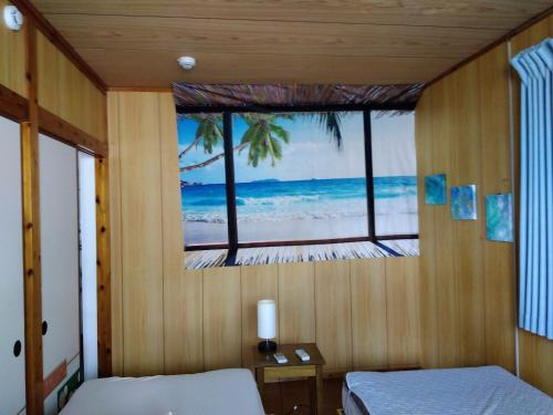 a bedroom with a window with a view of the beach at Miyagi Apartment Tomari in Naha