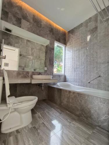 a bathroom with a toilet and a tub and a sink at Villa Cisarua RJS in Brujul