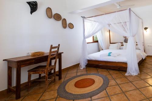 a bedroom with a bed and a desk and a table at Royal Sakalava in Diego Suarez