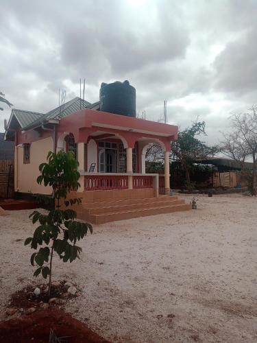 a small house with a pink roof and stairs at VOI HIGHWAY BNB in Voi