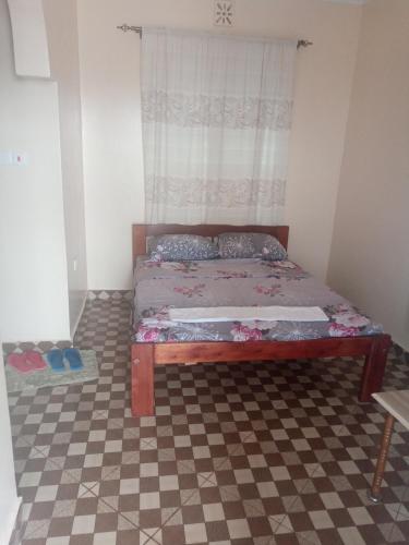 ein Schlafzimmer mit einem Bett mit einem karierten Boden in der Unterkunft VOI HIGHWAY BNB in Voi