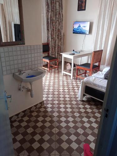 ein Bad mit einem Waschbecken, einem Bett und einem Schreibtisch in der Unterkunft VOI HIGHWAY BNB in Voi