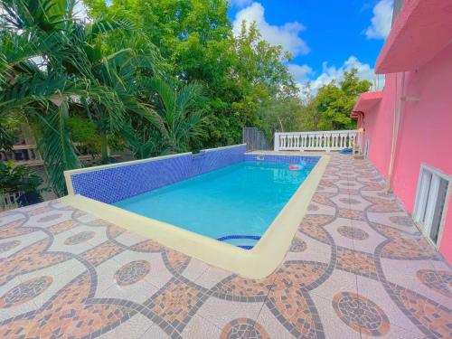 - une piscine avec banc à côté d'une maison rose dans l'établissement A taste of Jamaica Lavern’s Place, à Ocho Rios