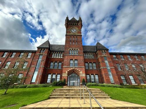 um grande edifício de tijolos com uma torre de relógio em Birch Hill Clock Tower em Rochdale