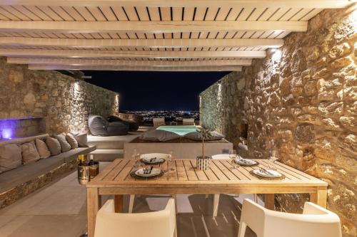 a stone walled patio with a wooden table and chairs at Mykonos Actor’s Villa. 2 BDRs, private mini-pool in Mikonos