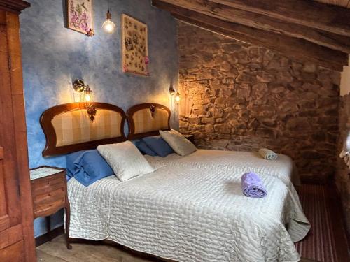 - une chambre avec un lit et un mur en pierre dans l'établissement Casa Rural Garzibaita, à Sumbilla