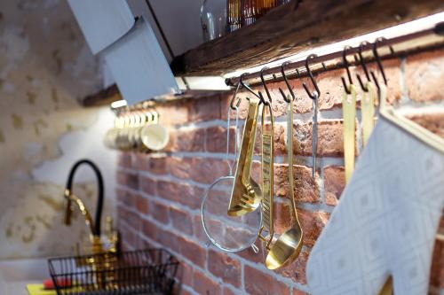 eine Küche mit Kupferutensilien, die an einer Ziegelwand hängen in der Unterkunft PORANEK W GÓRACH in Ustrzyki Dolne