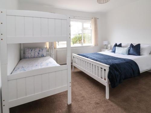 two white bunk beds in a white bedroom at Beach Retreat in Prestatyn