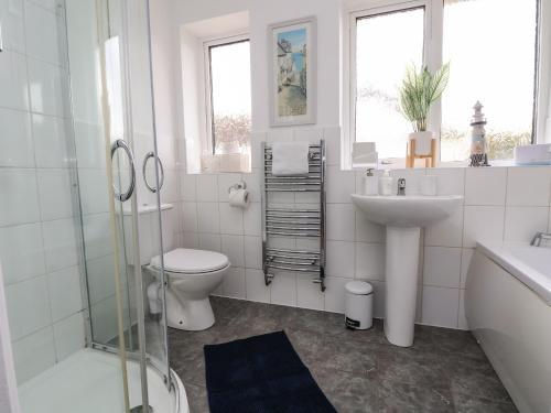 a white bathroom with a toilet and a sink at Beach Retreat in Prestatyn