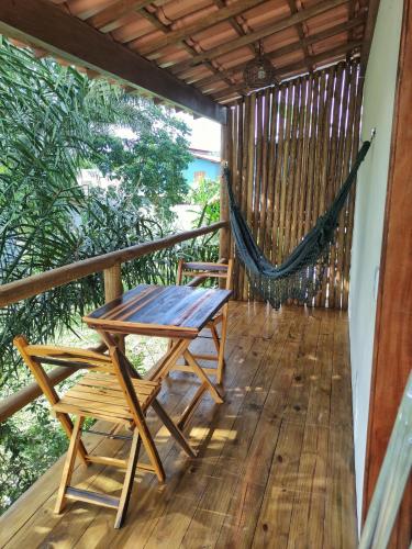 a porch with a hammock and a table and a swing at Acalanto do Sargi in Uruçuca