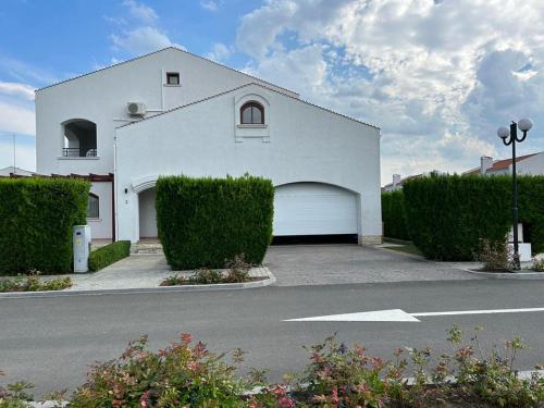 a white house with a garage and some bushes at Vila Y2 in Arena Regia Residence - Adults only-14 and above- No parties allowed in Mamaia Nord