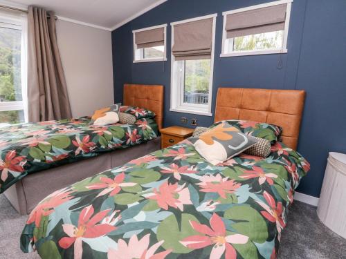 2 łóżka w pokoju z niebieskimi ścianami i oknami w obiekcie Robin Lodge w mieście Crieff