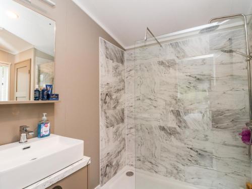 baño blanco con ducha y lavamanos en Robin Lodge, en Crieff