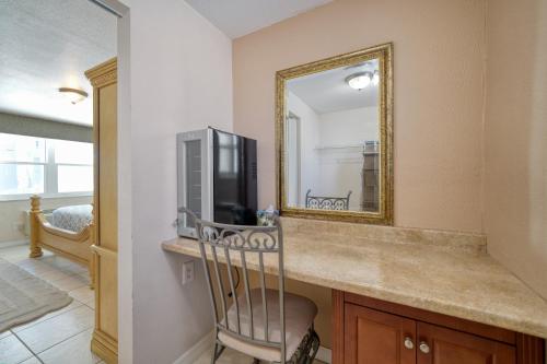 a bathroom with a counter with a mirror and a television at Camelot Beach Suites in Clearwater Beach