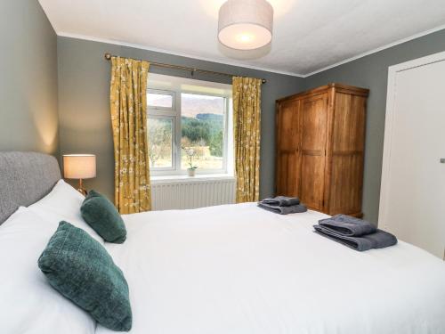 a bedroom with a large white bed and a window at Ben Grianan in Aberfeldy