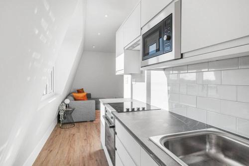 a kitchen with a sink and a microwave at Tranquil 2-Bed Oasis in Tooting 20 min to Central in London