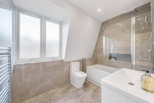 a bathroom with a toilet and a tub and a sink at Tranquil 2-Bed Oasis in Tooting 20 min to Central in London