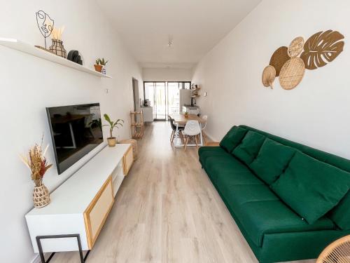 a living room with a green couch and a table at Casa Piscina Aquecida Canto Del Mare in São Sebastião