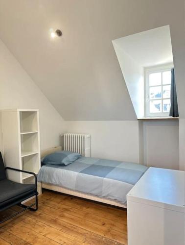 ein Schlafzimmer mit einem Bett und einem Stuhl darin in der Unterkunft Vents Marins in Saint-Quay-Portrieux