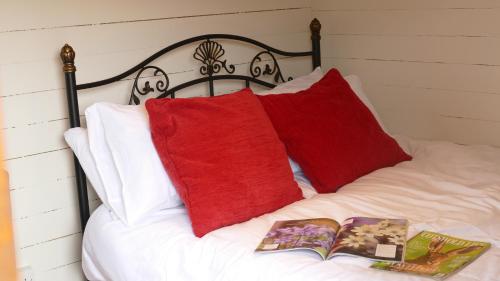 uma cama com duas almofadas vermelhas e um livro em The Freight Wagon 