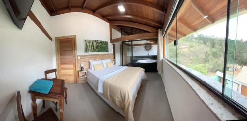 - une chambre avec un grand lit et une grande fenêtre dans l'établissement Pousada Mar Mineiro Macacos, à Nova Lima