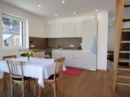 a kitchen with a white table and chairs and a table and a kitchen at Haus am Brunnen in Prato allo Stelvio