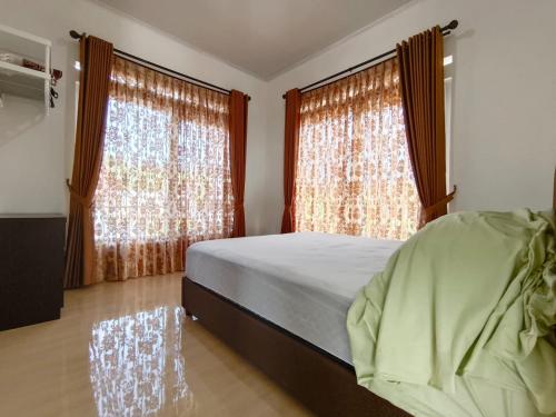 een slaapkamer met een bed en 2 grote ramen bij Villa Cisarua KB Isyana in Brujul