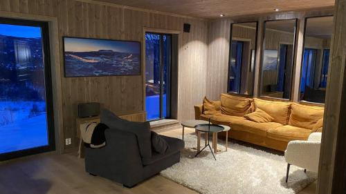 a living room with a couch and a chair at Budalstølen-ny og flott hytte-sentral beliggenhet in Geilo