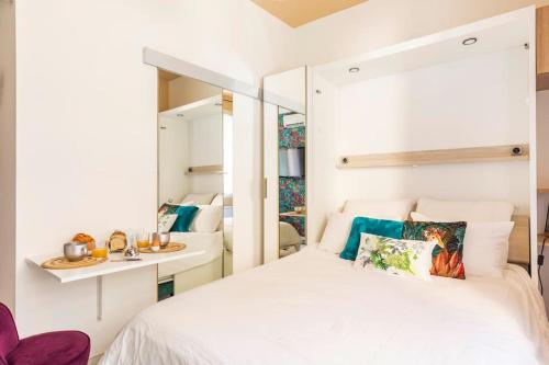 une chambre avec un lit blanc et un miroir dans l'établissement Tapualiki studio cosy tout confort, à Cannes