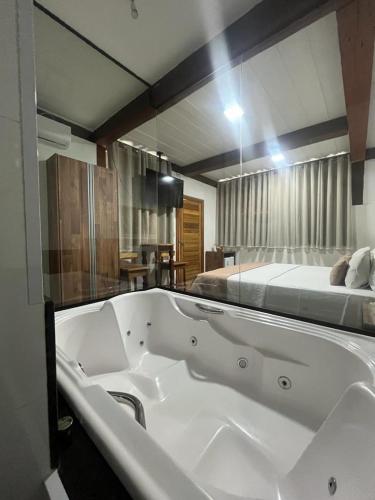 a large bath tub in a room with a bed at Pousada Mar Mineiro Macacos in Nova Lima