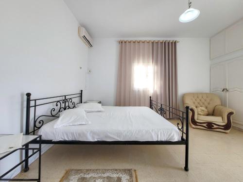 a bedroom with a bed and a chair and a window at Yassmine in Djerba