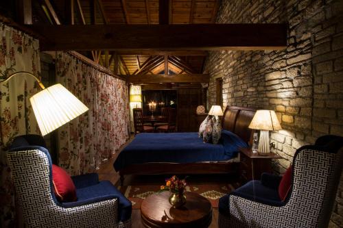 a bedroom with a bed and two chairs at Nine Furlongs, Binsar Wildlife Sanctuary in Almora