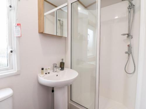 uma casa de banho branca com um lavatório e um chuveiro em Silverdale View em Ganton