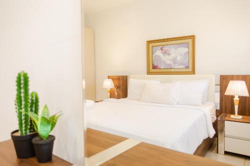 ein Schlafzimmer mit einem weißen Bett und einer Topfpflanze in der Unterkunft Accra Luxury Apartments @ Pine Court in Cantonments
