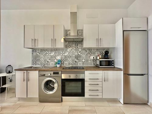 a kitchen with white cabinets and a washing machine at Cotillo Sol en el centro del Cotillo, 1 minuto de la playa, 2 habitaciones, terraza y WIFI in Cotillo