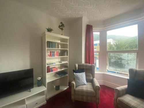 a living room with a tv and a chair and a window at Peaceful Coastal Apartment in Ventnor