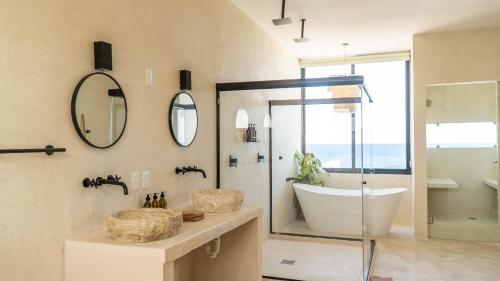 ein Badezimmer mit einer Badewanne, einem Waschbecken und einem Spiegel in der Unterkunft Villa Saadhu with fantastic oceanview in Isla Mujeres