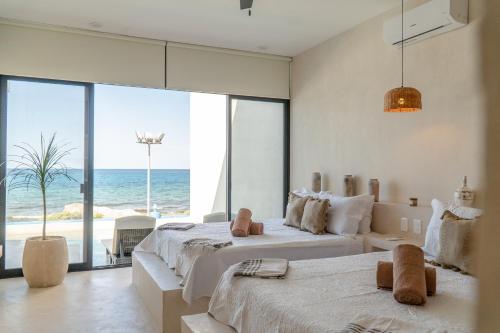 two beds in a bedroom with a view of the ocean at Villa Saadhu with fantastic oceanview in Isla Mujeres