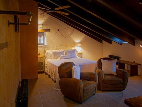 een slaapkamer met een wit bed en 2 stoelen bij Hotel Posada Al Vent - Adults Only in Coscojuela de Sobrarbe