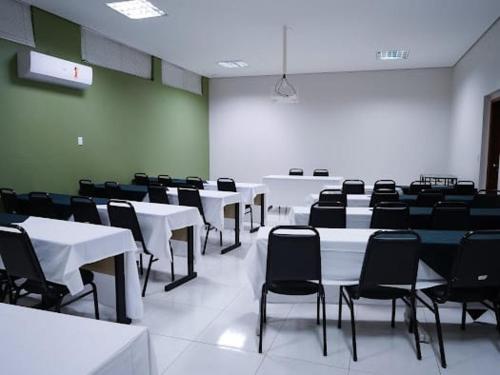 a room with white tables and black chairs at Attiê Park Hotel in Uberlândia