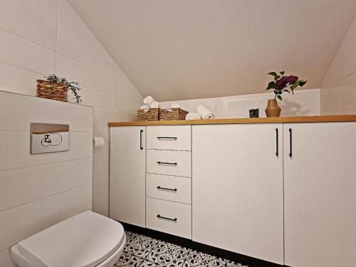 a bathroom with white cabinets and a toilet at Karczma Ostoya in Jasionka