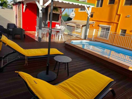 a deck with yellow chairs and a swimming pool at Appartement d'une chambre avec piscine privee jardin clos et wifi a Les Abymes in Les Abymes