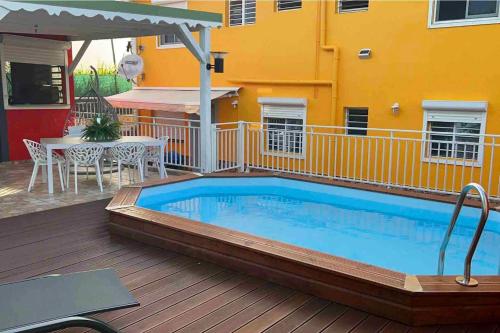 a swimming pool on a deck next to a yellow building at Appartement charmant à Les Abymes avec piscine privée, 60m² in Les Abymes