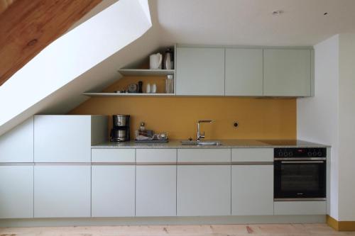 a kitchen with white cabinets and a staircase at Villa Anna in Solda